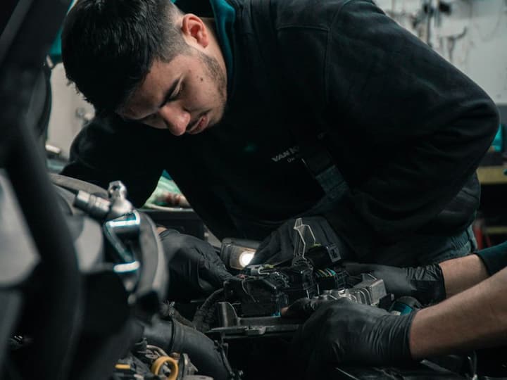Stock photo: a technician working under the hood of a car in a service bay